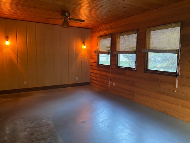 empty room featuring concrete floors, ceiling fan, wooden ceiling, and wood walls