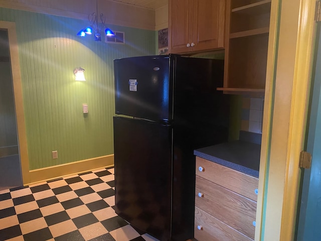 kitchen featuring backsplash, an inviting chandelier, and black refrigerator