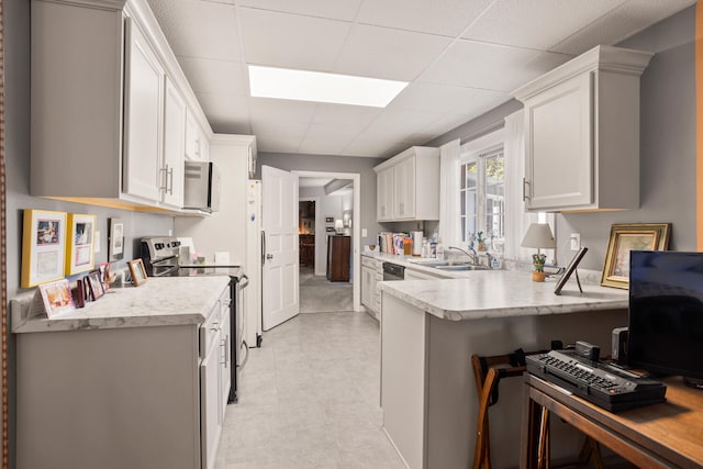 27 Hickory Ln, White Heath, IL 61884 - kitchen featuring stainless steel range with electric cooktop, a peninsula, light countertops, white cabinetry, and a paneled ceiling