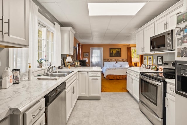 27 Hickory Ln, White Heath, IL 61884 - kitchen with appliances with stainless steel finishes, open floor plan, white cabinetry, a paneled ceiling, and a peninsula