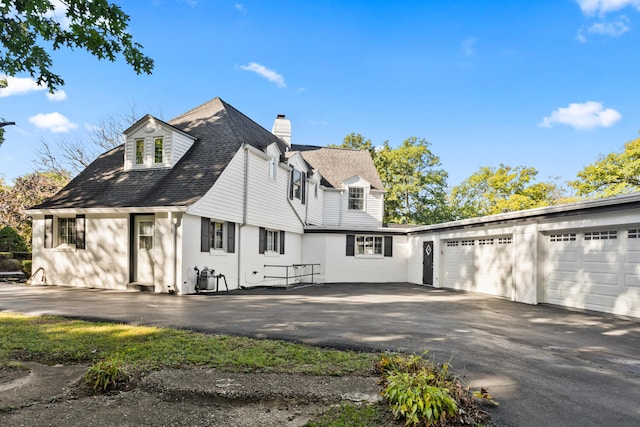 27 Hickory Ln, White Heath, IL 61884 - view of property exterior featuring asphalt driveway, a chimney, a shingled roof, and an attached garage