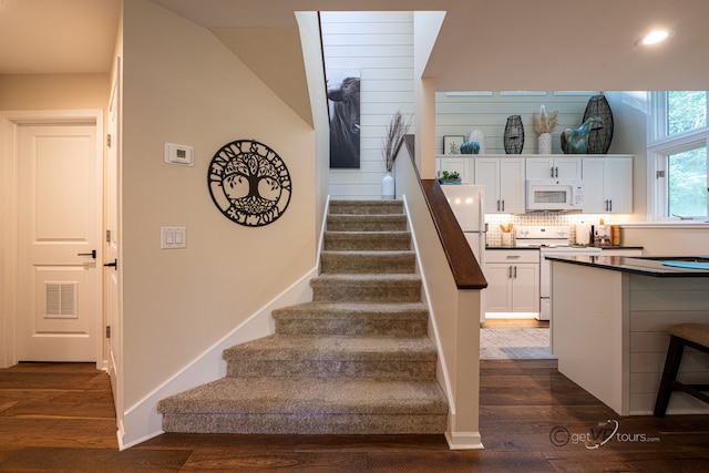 stairs with vaulted ceiling and hardwood / wood-style flooring