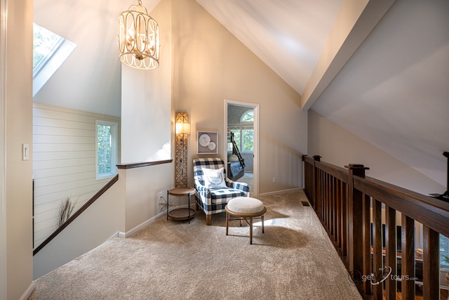 sitting room with a skylight, high vaulted ceiling, an inviting chandelier, and carpet