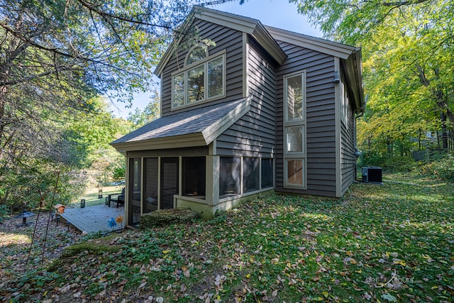 rear view of property featuring a lawn, a sunroom, and central AC