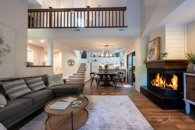 living room with a towering ceiling, a multi sided fireplace, and dark hardwood / wood-style flooring