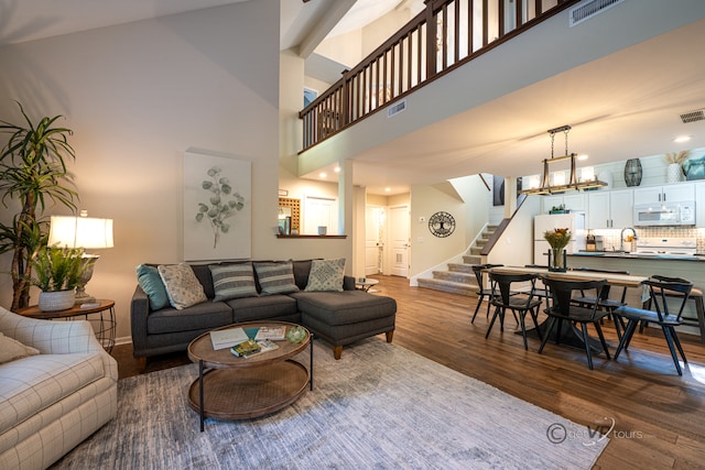 living room with a towering ceiling and wood-type flooring