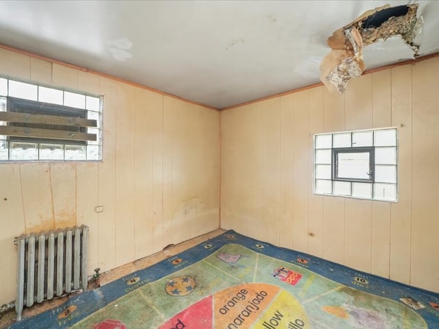 empty room featuring wooden walls and radiator