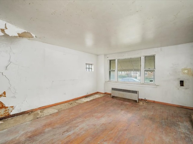 unfurnished room featuring radiator heating unit and hardwood / wood-style flooring