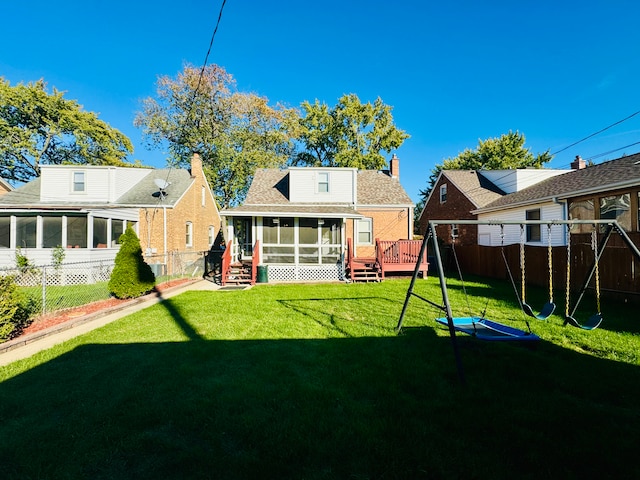 back of house featuring a yard, a sunroom, and a wooden deck