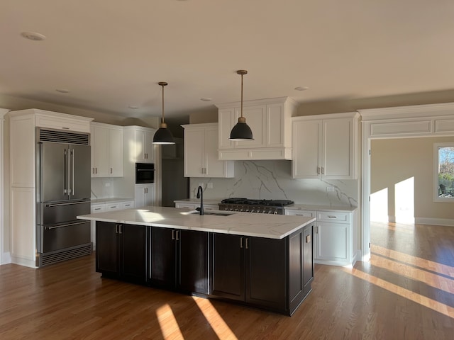 kitchen featuring decorative light fixtures, appliances with stainless steel finishes, sink, and wood-type flooring