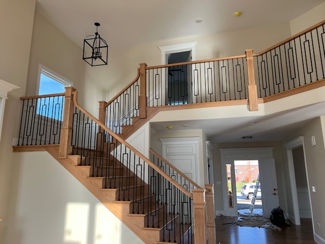 stairway featuring hardwood / wood-style flooring, plenty of natural light, and a notable chandelier