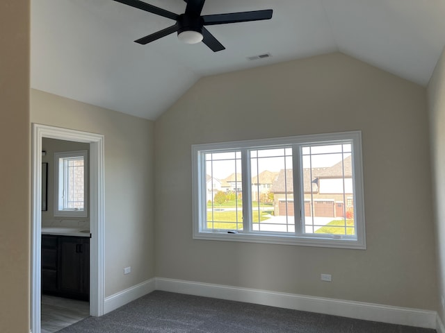 carpeted empty room featuring ceiling fan, lofted ceiling, and a healthy amount of sunlight