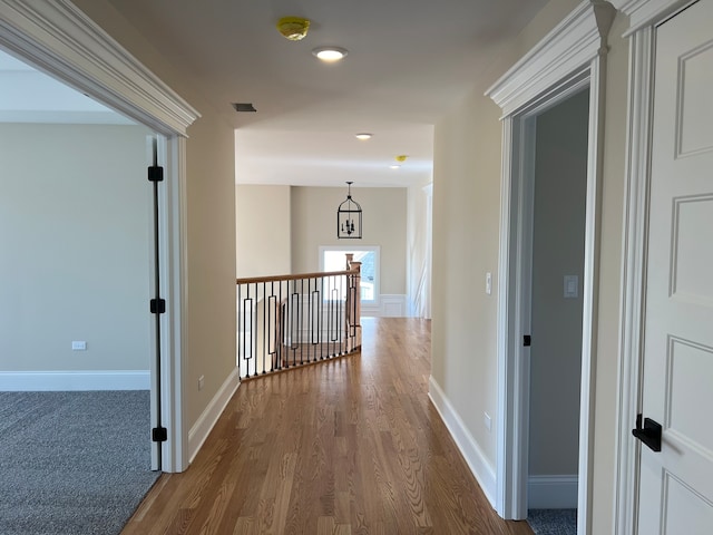 hall with hardwood / wood-style floors and an inviting chandelier