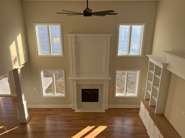 unfurnished living room with a premium fireplace, plenty of natural light, dark hardwood / wood-style floors, and ceiling fan