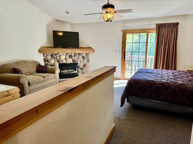 bedroom with access to outside, a stone fireplace, carpet floors, and ceiling fan