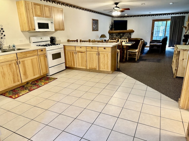 kitchen with ceiling fan, white appliances, light colored carpet, sink, and kitchen peninsula