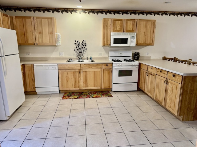 kitchen with white appliances, light tile patterned floors, sink, and kitchen peninsula