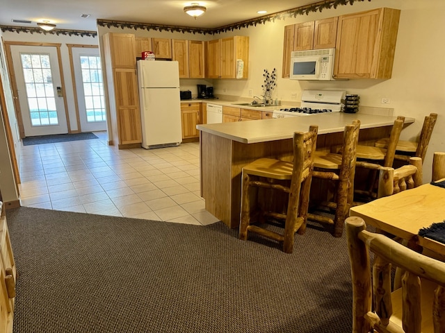 kitchen featuring light tile patterned flooring, kitchen peninsula, white appliances, and sink