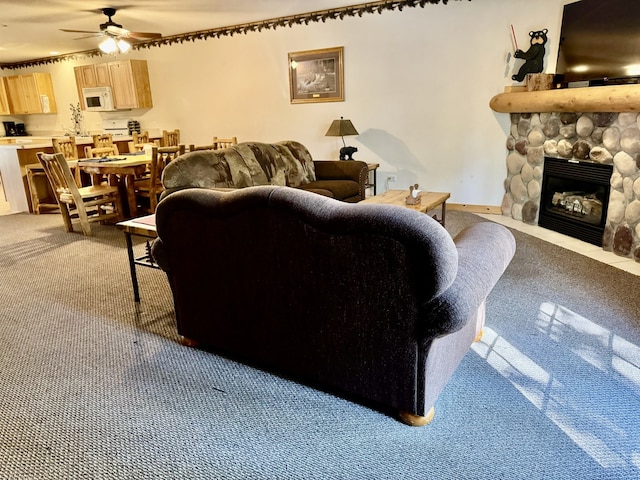 living room with a fireplace, light colored carpet, and ceiling fan