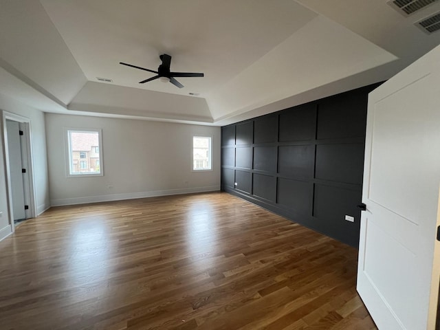 8673 High Stone Way, Frankfort, IL 60423 - unfurnished living room with ceiling fan, visible vents, a decorative wall, wood finished floors, and a tray ceiling