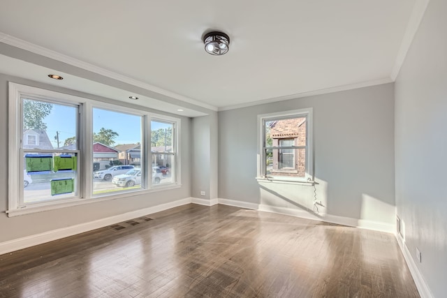 spare room featuring plenty of natural light, crown molding, and dark hardwood / wood-style flooring