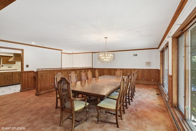 dining space featuring light colored carpet, an inviting chandelier, crown molding, and wood walls