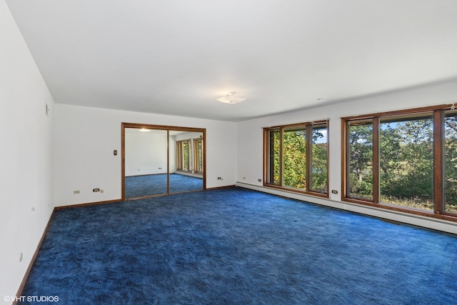 carpeted spare room with a baseboard heating unit