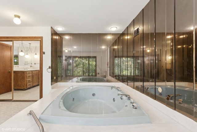 bathroom with vanity and tiled tub