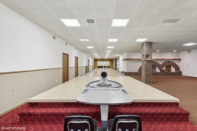 dining space with a paneled ceiling, a bowling alley, carpet floors, and a fireplace