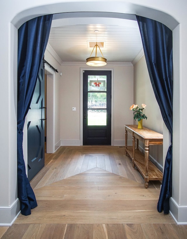 foyer featuring a barn door, ornamental molding, wood ceiling, and light wood-type flooring