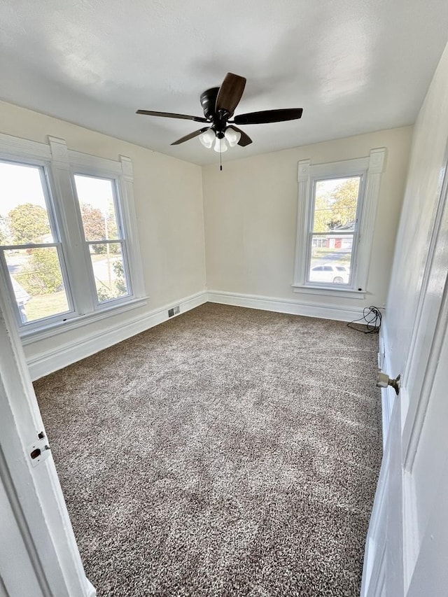 carpeted spare room with plenty of natural light and ceiling fan