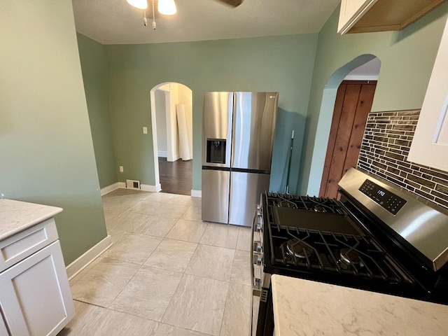 kitchen featuring appliances with stainless steel finishes, tasteful backsplash, ceiling fan, white cabinets, and light tile patterned flooring