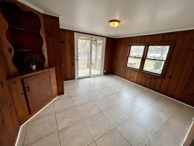 unfurnished room featuring wood walls, light tile patterned floors, and crown molding