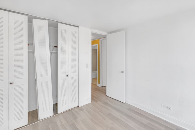 unfurnished bedroom featuring multiple closets and light wood-type flooring