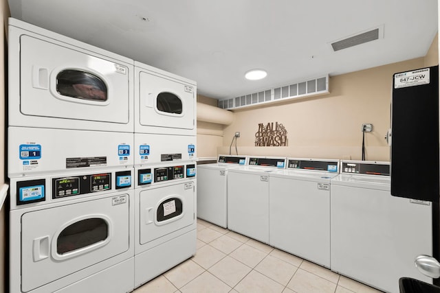 washroom with washing machine and dryer, light tile patterned floors, and stacked washer / drying machine