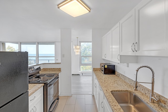 kitchen featuring sink, black / electric stove, refrigerator, a water view, and a healthy amount of sunlight