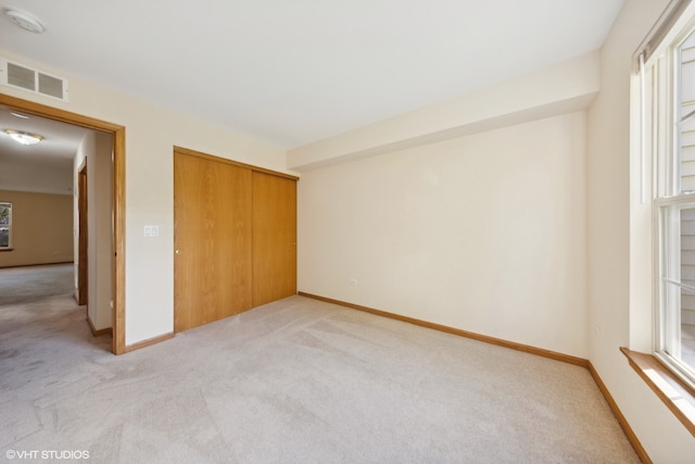 unfurnished bedroom with light colored carpet and a closet