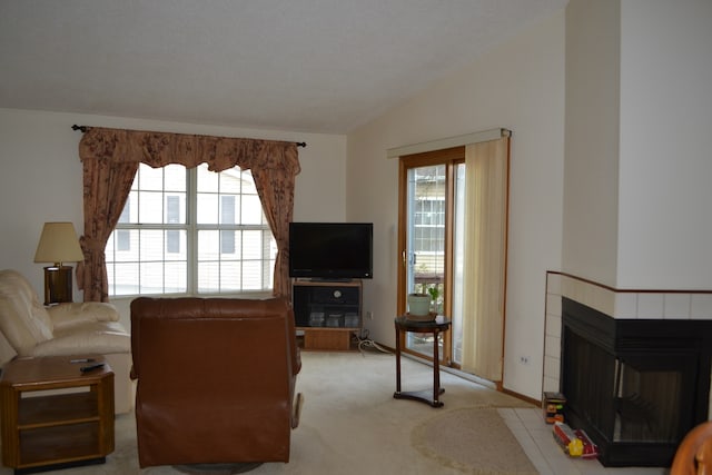 carpeted living room with a fireplace, vaulted ceiling, and a healthy amount of sunlight