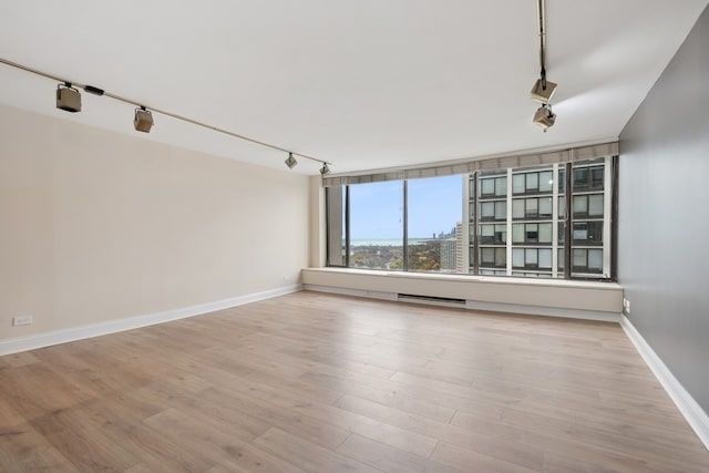 empty room with light hardwood / wood-style flooring and rail lighting