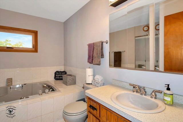 bathroom with vanity, toilet, and tiled bath