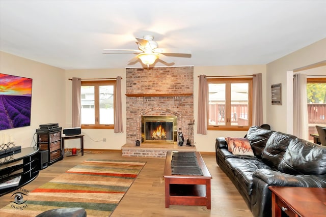 living room with a wealth of natural light, a brick fireplace, and hardwood / wood-style flooring