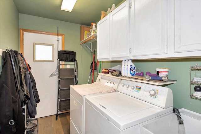 laundry room featuring independent washer and dryer, light wood-type flooring, and cabinets