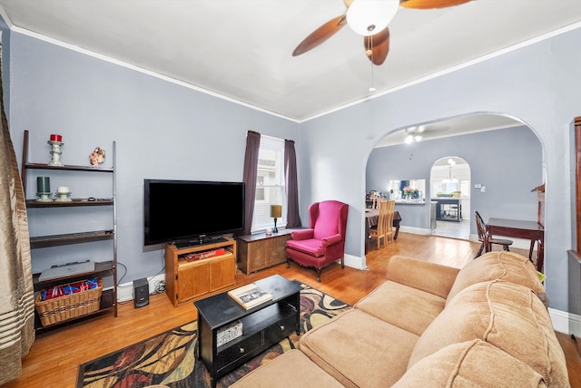 living room featuring hardwood / wood-style flooring, ceiling fan, and crown molding