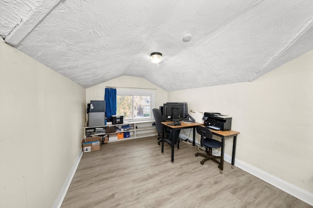 office space with a textured ceiling, vaulted ceiling, and light hardwood / wood-style flooring