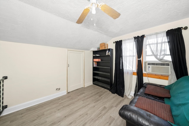 living area with a textured ceiling, vaulted ceiling, ceiling fan, and light hardwood / wood-style flooring