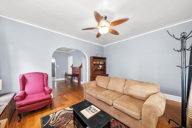 living room featuring hardwood / wood-style floors, ceiling fan, and crown molding