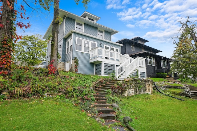 rear view of house featuring a lawn and a wooden deck