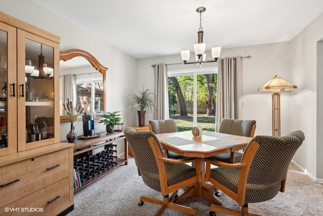 carpeted dining room with an inviting chandelier