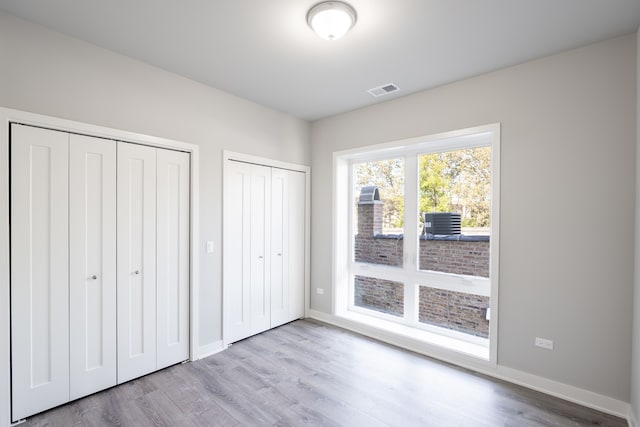 unfurnished bedroom featuring multiple closets and light hardwood / wood-style flooring