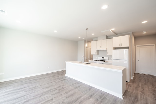 kitchen with white appliances, sink, light hardwood / wood-style floors, white cabinetry, and decorative light fixtures